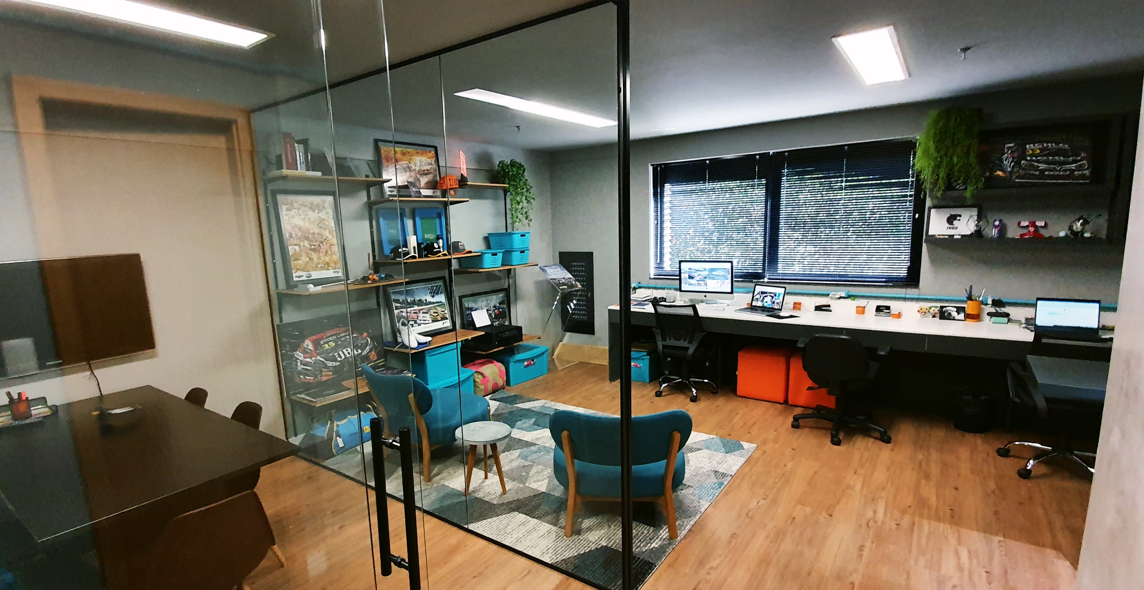 Escritório da SOMOZ Brands + Sports — sala com mesa de reunião, decoração com miniaturas de carros e capacetes do automobilismo